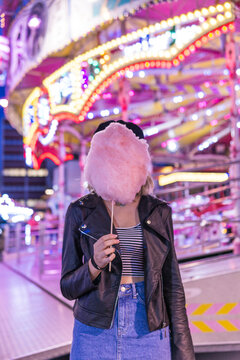 Teenage girl hiding her face behind pink candyfloss at fair