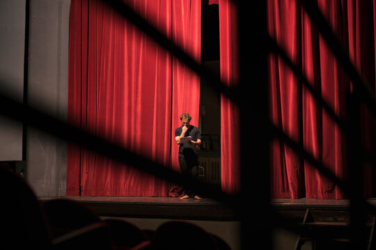 Barefoot actor standing on theatre stage studing the script