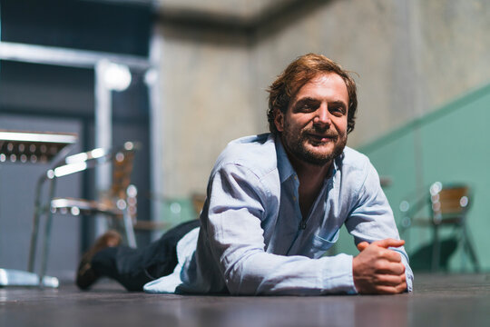 Portrait of smiling actor lying on theatre stage