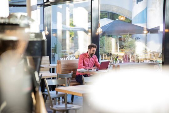 Young man using laptop in a cafe