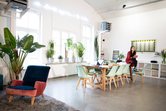 Woman sitting on table in modern office