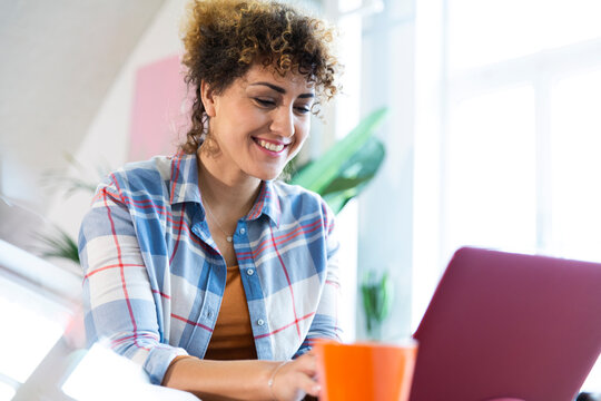 Smiling woman using laptop in office