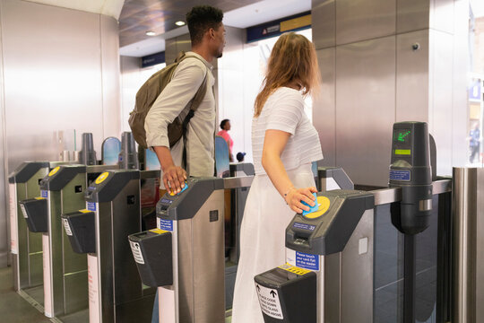 Young couple passing subway gate with electronic tickets