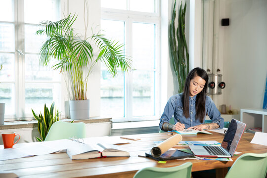 Woman working at table in modern office taking notes