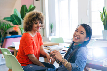Two happy women in modern office with video projector on table