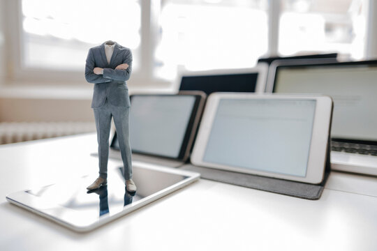 Headless businessman figurine standing on digital tablet on a desk