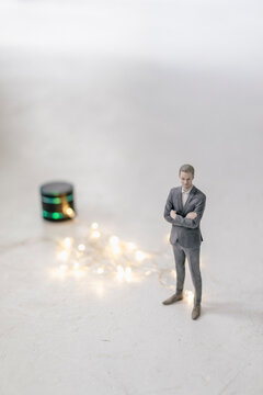 Miniature businessman figurine standing next to smart home loudspeaker with chain of lights