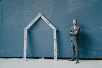 Pastic figurine, businessman and pocket rule as house