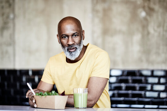 Portrait of mature businessman having lunch break in office