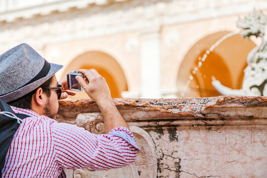 Italy, Marche, Loreto, mid adult traveler using action cam at a fountain