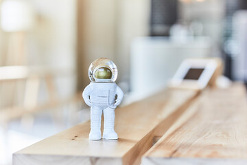Miniature astronaut figurine on wooden bench - obrazy, fototapety, plakaty