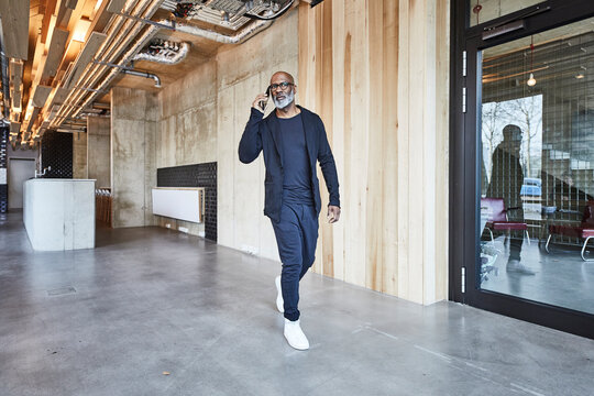 Mature businessman on cell phone walking in modern office