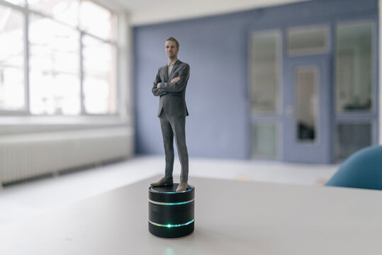Miniature businessman figurine standing on smart home loudspeaker