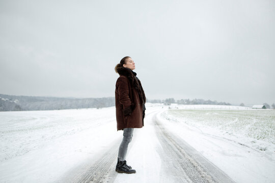 Mature woman standing on field way in winter