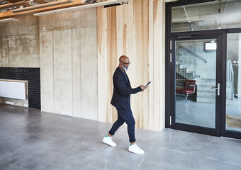 Mature businessman with cell phone walking in modern office