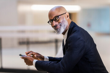 Portrait of smiling mature businessman with cell phone