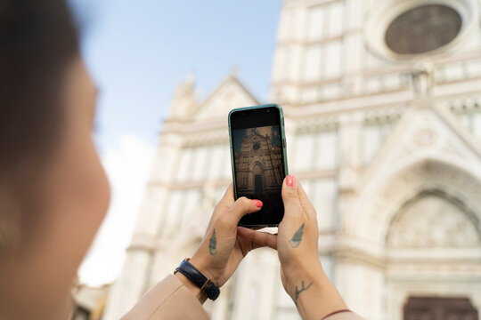 Woman taking smartphone picture of Santa Croce church, Florence, Italy