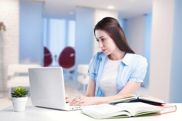 Caucasian female student working from home writing, sitting next to books