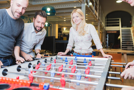 Happy colleagues playing foosball in office