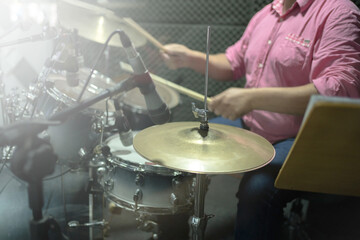 man dressed in pink playing acoustic drums. professional drums with microphones and acoustic isolation. dissemination to music schools or festivals or musical performances