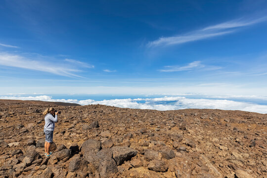 USA, Hawaii, Mauna Kea volcano, female tourist taking a photo of volcanic landscape