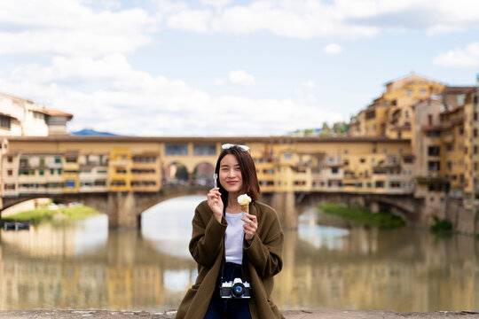 Italy, Florence, young tourist woman eating an ice cream cone at at Ponte Vecchio