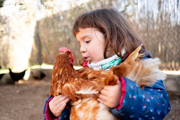 Toddler girl talking to chicken on her arms