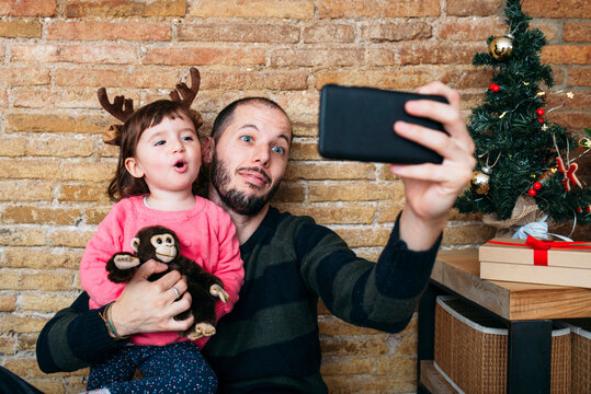 Portrait of father and little daughter taking selfie with smartphone at Christmas time