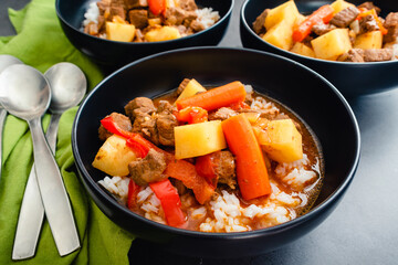Bowls of Mechado Filipino Beef Stew Served Over White Rice: Braised beef in tomato sauce with chunks of potatoes and carrots