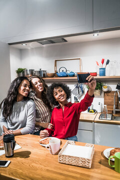 Three happy women posing for a selfie at table