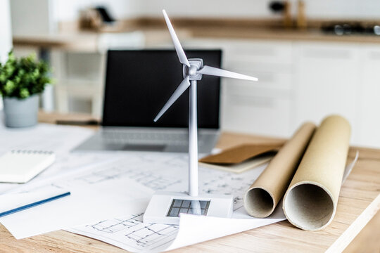 Wind turbine model, construction plan and laptop on table in office
