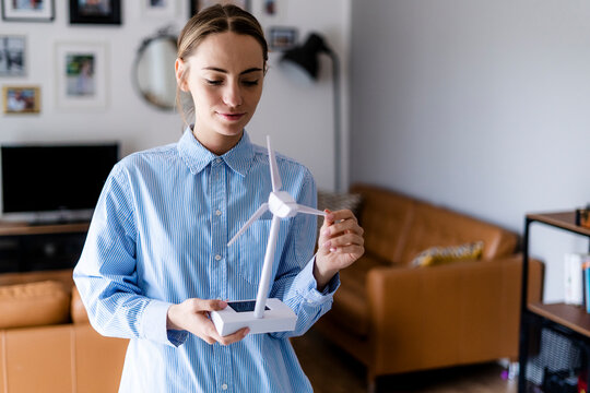 Confident woman in office holding wind turbine model
