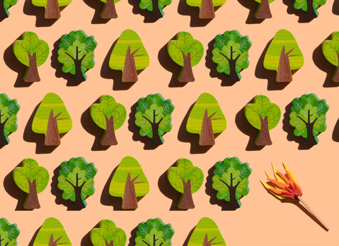 Studio shot of burning match threatening rows of small wooden trees