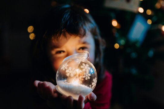 Little girl holding lighted glass ball at Christmas time