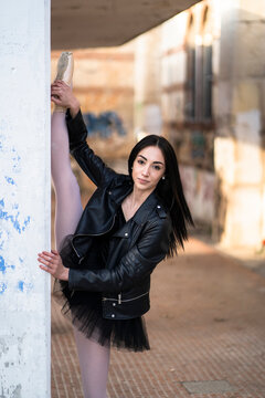 Italy, Verona, portrait of young woman wearing leather jacket and tutu stretching