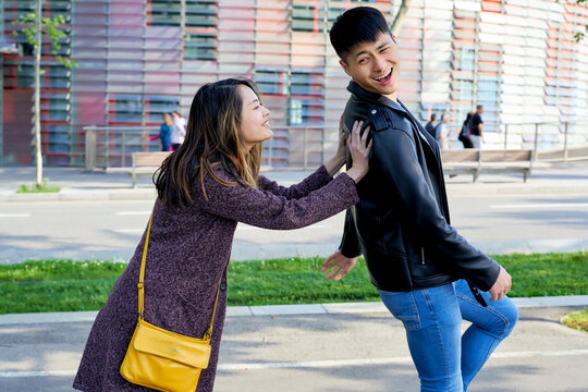Happy woman pushing boyfriend down the street, Barcelona, Spain