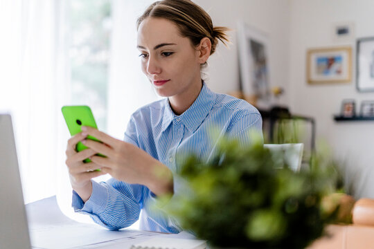Woman in office using cell phone at table