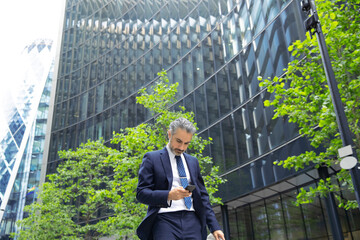 Businessman texting through mobile phone outside office building in city