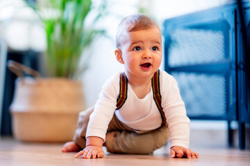 Cute baby boy playing while sitting on floor at home