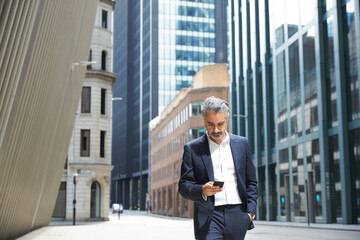 Businessman texting through mobile phone in city