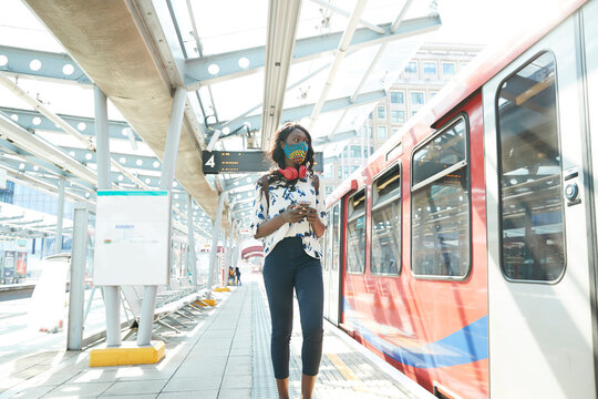 Businesswoman wearing face mask using mobile phone while standing at station platform