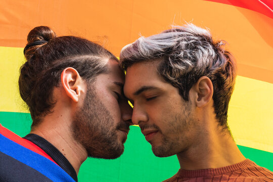 Affectionate man flirting with male partner against rainbow scarf