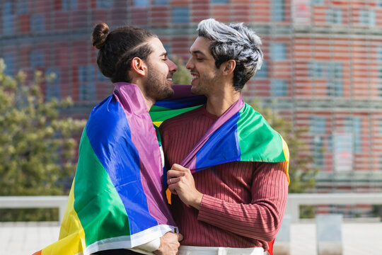 Smiling affectionate man with rainbow scarf looking at male partner in park