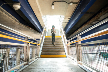 Businesswoman using mobile phone while walking on staircase in subway station