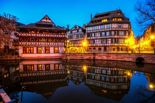 France, Grand Est, Strasbourg, Half-timbered houses reflecting in old town canal at dusk