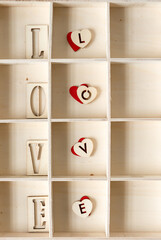 the word love (luv) in wooden letters arranged in a shallow box with square compartments