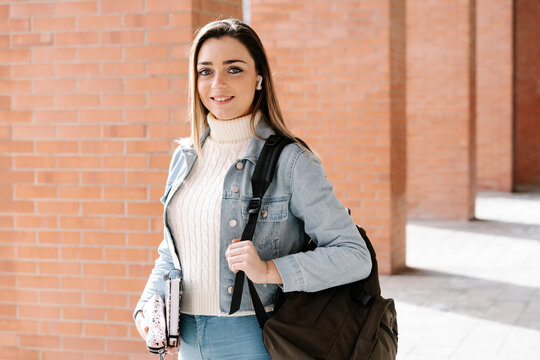 Smiling university student with bag and book in campus