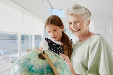 Grandmother and granddaughter looking at globe in a villa