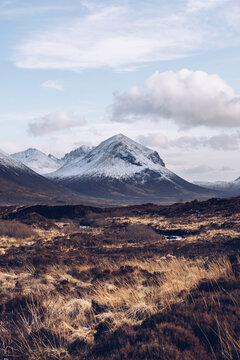 UK, Scotland, Brown grassy landscape of Isle of Skye in winter with snowcapped mountains in background