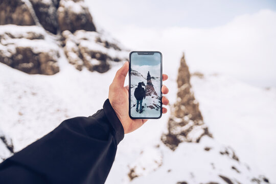 UK, Scotland, Arm of man taking smart phone photos at Isle of Skye in winter